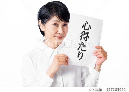 心得たりと書かれた紙を両手で持ちニヤリと笑うシニア女性 137285922