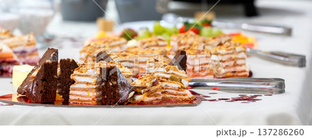 Assorted layered cakes and pastries table 137286260