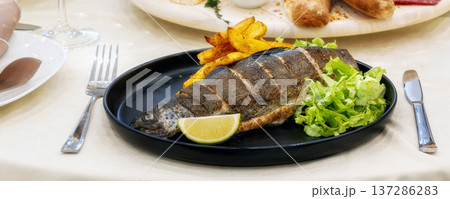 Roast trout with potatoes and lettuce salad banner 137286283