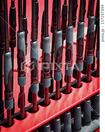 Collection of fishing rods neatly arranged on a display stand in a retail store during daylight hours Collection of fishing rods neatly arranged on a display stand in a retail store during daylight hours 137287894