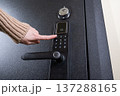 A woman opens a modern smart door lock with a digital keypad using a code. 137288165
