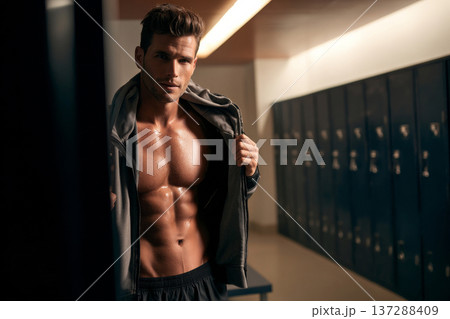 athletic man with defined abs holding sports jacket over shoulder in locker room, clean bright 137288409