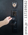 A woman opens a modern smart door lock using a contactless key. 137289682