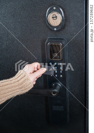 A woman opens a modern smart door lock using a contactless key. 137289682