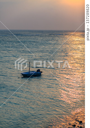 Small boat floats calm ocean at golden sunset Small boat floats calm ocean at golden sunset 137289820