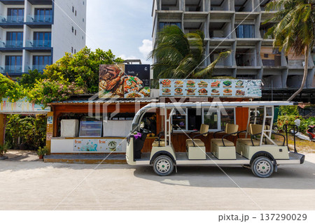 Sunlit beachside tour vehicle near a food stall 137290029