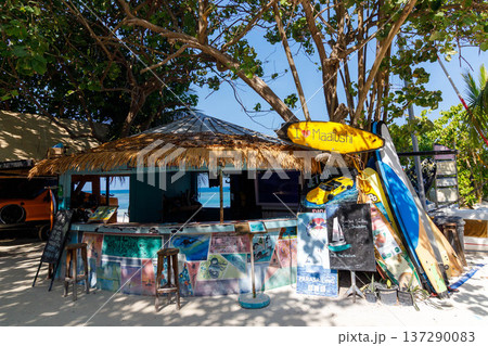 Sunlit beach bar with tropical thatch roof 137290083