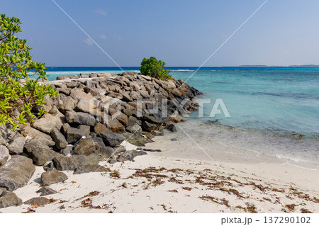 Sunlight glints off turquoise waters beside rocky shore 137290102