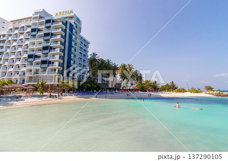 Sunlit beach meets turquoise waters and a towering resort Sunlit beach meets turquoise waters and a towering resort 137290105