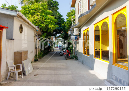 Sunlit alley with vibrant yellow shopfronts 137290135