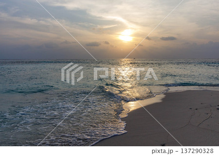 Sun dips low, casting golden glow across ocean's surface 137290328