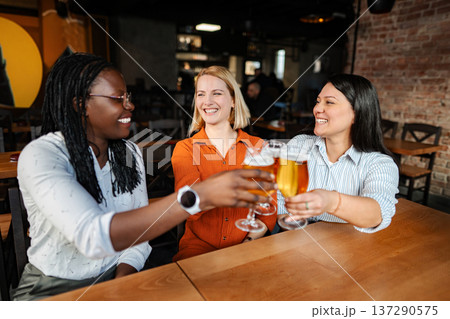 Friends toasting beer celebrating diverse friendship in a bar Friends toasting beer celebrating diverse friendship in a bar 137290575