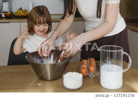 Mother and little daughter baking together in modern kitchen at home, happy family cooking and spending time together 137291156