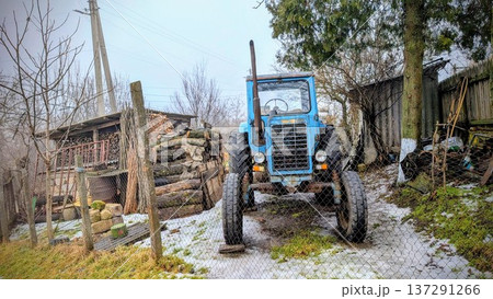 Muddy Rural Tractor. Scene Featuring Blue Tractor Amidst Muddy Farm Environment During Cold Winter Months Muddy Rural Tractor. Scene Featuring Blue Tractor Amidst Muddy Farm Environment During Cold Winter Months 137291266