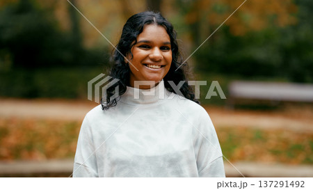 Indian woman smiling enjoying autumn season outdoors Indian woman smiling enjoying autumn season outdoors 137291492