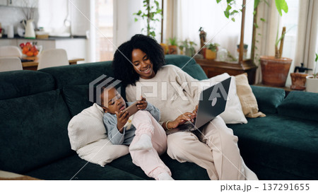 Mother and daughter using devices on couch Mother and daughter using devices on couch 137291655