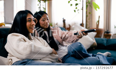 Two women friends watching television while relaxing at home Two women friends watching television while relaxing at home 137291677