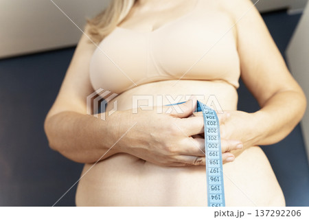 Woman measuring waist with tape for health monitor Woman measuring waist with tape for health monitor 137292206