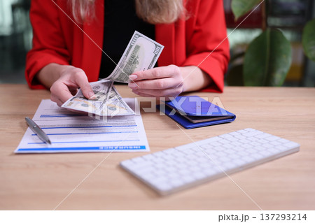 Counting money and signing documents during a business meeting in a modern office setting Counting money and signing documents during a business meeting in a modern office setting 137293214