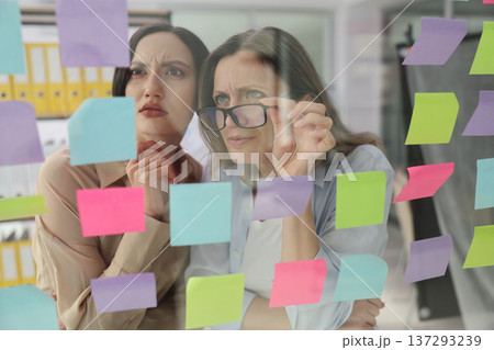 Team brainstorming ideas through colorful sticky notes in a modern office setting during the day 137293239