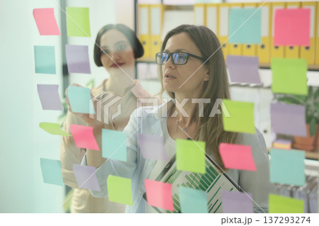 Creative brainstorming session with sticky notes in a vibrant office environment Creative brainstorming session with sticky notes in a vibrant office environment 137293274