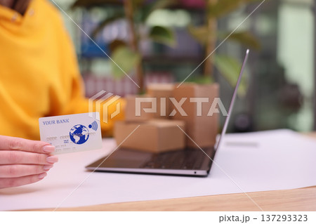 Shopping online with a credit card while surrounded by packages in a cozy home workspace Shopping online with a credit card while surrounded by packages in a cozy home workspace 137293323