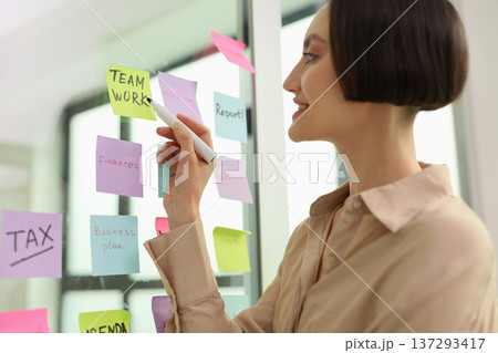 Creative collaboration in a bright office space showcases the art of teamwork through colorful sticky notes on a glass board 137293417