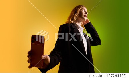 Business woman presenting smartphone toward camera on yellow green gradient background. Business woman presenting smartphone toward camera on yellow green gradient background. 137293565