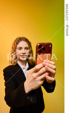 Young business woman taking selfie with smartphone on yellow green gradient background. 137293566