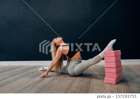 Young Female Practices Seated Side Stretch Exercise In Indoor Gym Space. Girl Stretching, Enjoying Fitness Training And Healthy Lifestyle. Yoga For Health 137293755