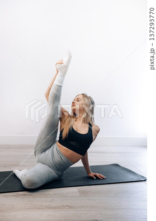 Young Female Practices Seated Side Stretch Exercise In Indoor Gym Space Focusing On Health. Girl Stretching, Enjoying Fitness Training Yoga And Healthy Lifestyle. Young Female Practices Seated Side Stretch Exercise In Indoor Gym Space Focusing On Health. Girl Stretching, Enjoying Fitness Training Yoga And Healthy Lifestyle. 137293770
