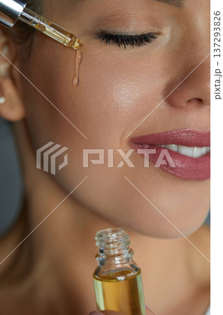 Woman Dropping Serum on Face. Model Girl Applying Serum Collagen Moisturizer from Pipette on Face close up. Positive Laughing Beautiful Woman. Concept of Face Skin Care. 137293826