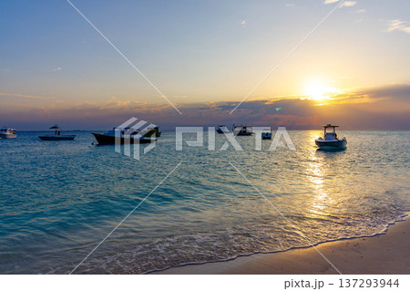 Golden sun dips low over calm turquoise sea 137293944