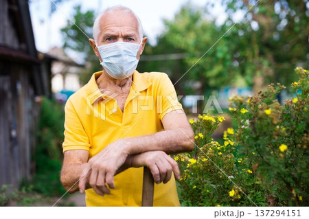 Portrait of adult farmer in protective mask with shovel on field 137294151