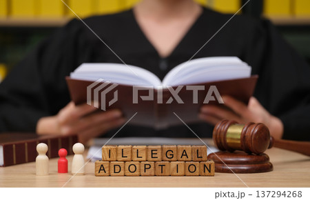 Courtroom scene highlights illegal adoption with judge, gavel, and legal books in focus during a serious discussion 137294268