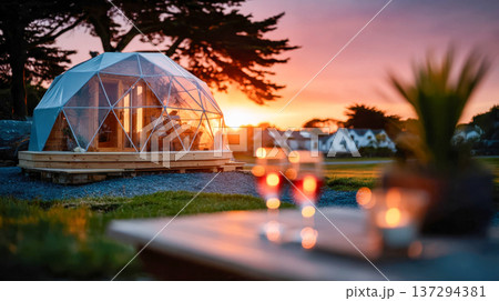 Luxury geodesic dome glamping cabin at sunset with warm golden light, modern eco retreat in nature 137294381