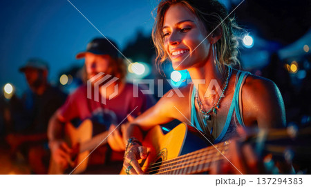 Smiling young woman playing acoustic guitar by a beach bonfire with friends in the background, warm firelight and night bokeh, cozy camping vibe 137294383