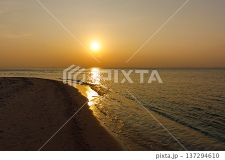 Golden sun sets over calm sea horizon 137294610