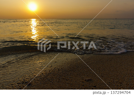 Sun dips low over calm ocean waters 137294704