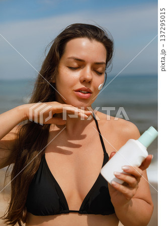 Beautiful woman applying sunscreen lotion on collarbone area at beach, skincare and sun protection concept with natural beauty and healthy skin Beautiful woman applying sunscreen lotion on collarbone area at beach, skincare and sun protection concept with natural beauty and healthy skin 137295015