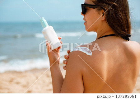 Woman Applying Suncream Sunscreen Lotion with Ocean Background Woman Applying Suncream Sunscreen Lotion with Ocean Background 137295061