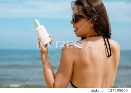Back View Woman Applying Suncream Sunscreen Lotion on Beach 137295069