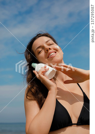 Relaxed woman with sunscreen lotion enjoying sunlight at beach, beauty and skincare summer concept Relaxed woman with sunscreen lotion enjoying sunlight at beach, beauty and skincare summer concept 137295087