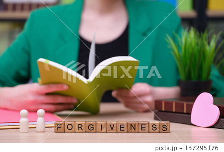Exploring the concept of forgiveness through reading in a cozy, serene workspace surrounded by greenery and colorful books Exploring the concept of forgiveness through reading in a cozy, serene workspace surrounded by greenery and colorful books 137295176