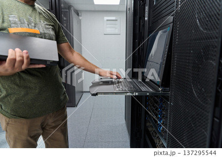 Data center technician using rack console laptop for server maintenance and IT network troubleshooting Data center technician using rack console laptop for server maintenance and IT network troubleshooting 137295544