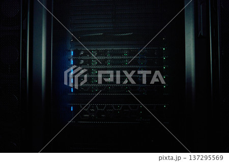 Dark server rack with glowing network equipment and status lights in a data center cabinet Dark server rack with glowing network equipment and status lights in a data center cabinet 137295569