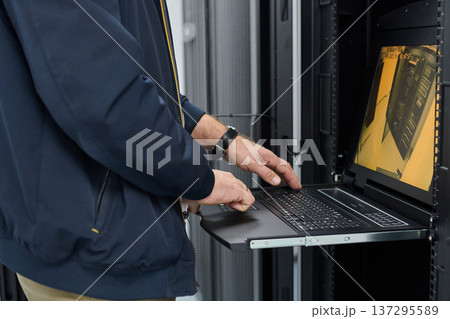 IT technician using a rack-mounted laptop to monitor servers during maintenance in a data center IT technician using a rack-mounted laptop to monitor servers during maintenance in a data center 137295589