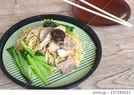 dry Chinese egg yellow noodles with red barbecue pork and cabbage on plate with wooden chopsticks dry Chinese egg yellow noodles with red barbecue pork and cabbage on plate with wooden chopsticks 137295633