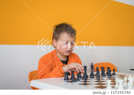 Serious school boy student playing chess in the classroom. Child with chess indoor Serious school boy student playing chess in the classroom. Child with chess indoor 137295740