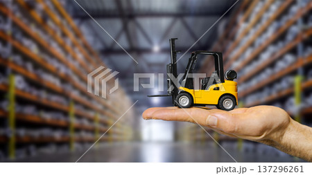 Forklift truck on hand in a large blurred warehouse. A creative concept showcasing logistics management Forklift truck on hand in a large blurred warehouse. A creative concept showcasing logistics management 137296261
